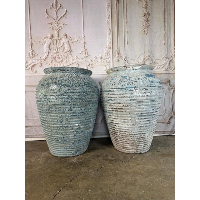 A striking pair of antique terracotta garden urns featuring a beautifully aged surface with traces of original blue...