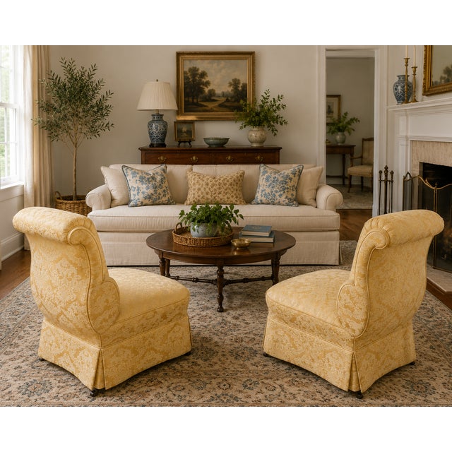 A distinctive pair of circa 1930s–1940s slipper chairs with dramatic scroll-over backs, low armless profiles, tailored...