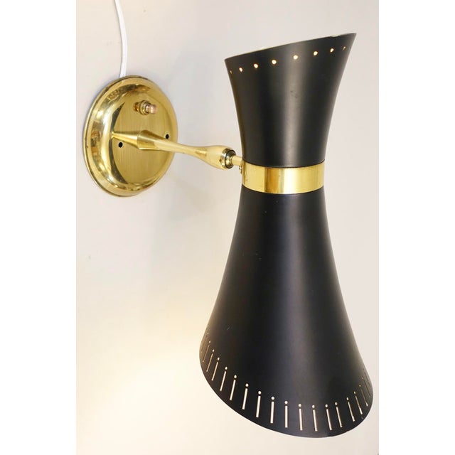 A dramatic and visually striking atomic Modern sculptural "Diablo (two light)" Brass & perforated enameled metal wall lamp...