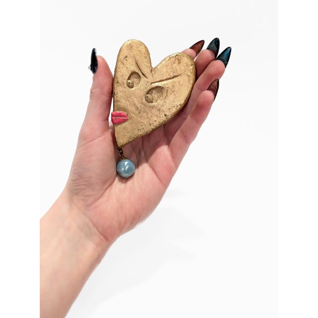 A fine signed Modern brooch. By BillyBoy*. In the form of a heart with eyes, red lips, and a dangling green iridescent...