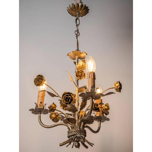 Smaller chandelier made of polychrome sheet metal artistically shaped as a bundle of leaves with flowers. The chandelier...