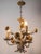 Smaller chandelier made of polychrome sheet metal artistically shaped as a bundle of leaves with flowers. The chandelier...