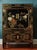 A charming vintage Chinoiserie accent cabinet featuring a glossy black lacquer finish with colorful floral, foliage, and...