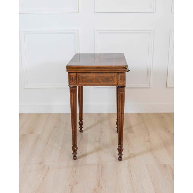 An elegant French Charles X period game table, circa 1820, masterfully crafted in mahogany with fine maple inlay...