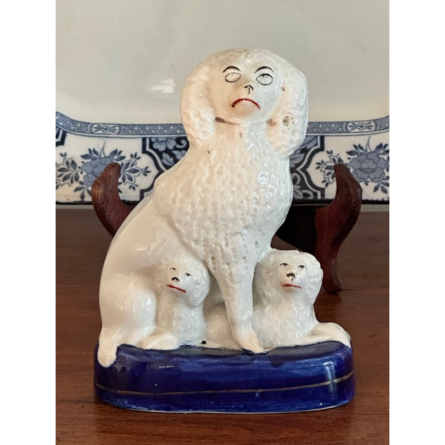 Sweet authentic antique Staffordshire dog figurine featuring a mom with her two pups peaking from under her legs. Made in...