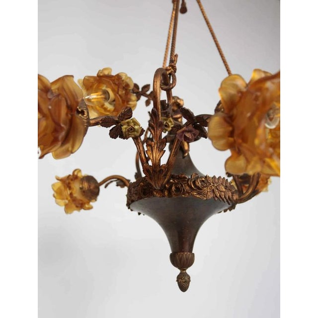 Brass chandelier with figurative decoration of amoretto (putto), which symbolizes a child carrying a cornucopia. Florally...