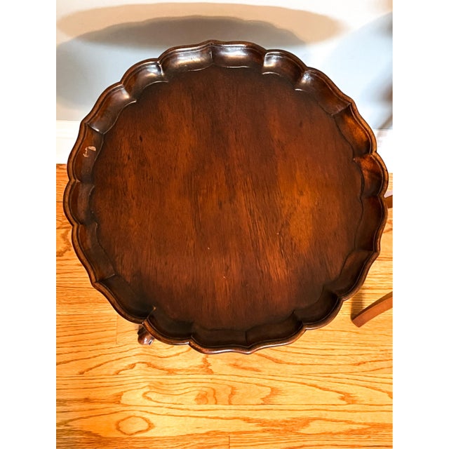 A vintage Chippendale style mahogany pie-crust side tea table on a tripod pedestal base with a round scalloped top, raised...