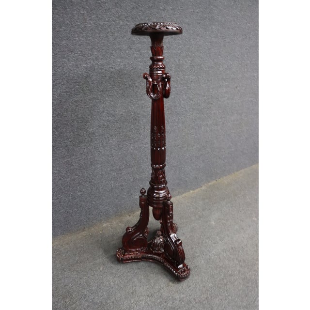 Carved mahogany pedestal or plant stand featuring an ornate tripod base, carved foliate and scroll details, and decorative...