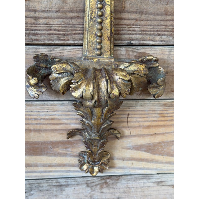 A striking pair of vintage gilt wall mounts featuring dramatic acanthus leaf detailing and a classic neoclassical...