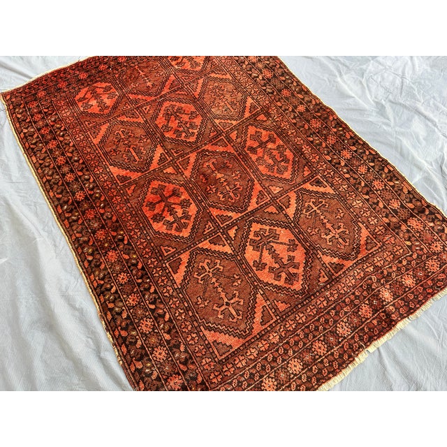 This hand-knotted Baluch rug features a grid of diamond compartments, each centered with a stylized cross-and-tree motif...