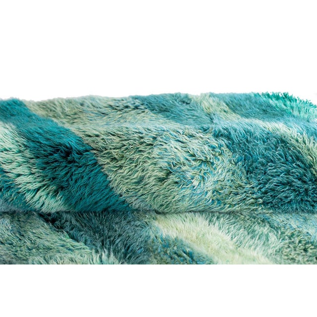 Stunning hand-knotted wool rug in calming shades of Turquoise, Aegean Blue, Taupe, Green Heron, Olivine, Storm Blue, and...