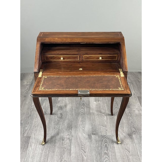 Elegant drop-front secretary desk in veneered wood, richly decorated with floral marquetry in the Louis XV style. The...