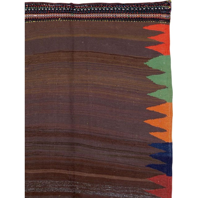 This Mid-20th century Persian flatweave kilim presents a strikingly minimalist composition centered on a broad, open field...