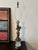 A beautifully detailed mid‑century brass lamp featuring a sculpted cherub standing atop a faceted cut‑glass base with a...