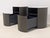The Poliform Onda nightstands feature a sleek, cylindrical design with a smooth taupe finish, an open upper shelf, and a...