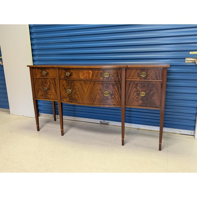 An exquisite Hepplewhite Colonial Revival bowfront sideboard, likely produced in the 40's or 50's. Expertly crafted with...