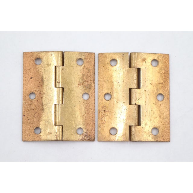 Vintage cabinet door hinges made of polished brass with flat tips, five knuckles, and a template hole pattern. The...
