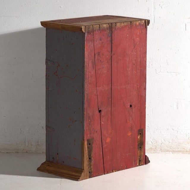 This antique painted cupboard in pine wood is a Central European rustic cabinet with a single door and crackled grey paint...