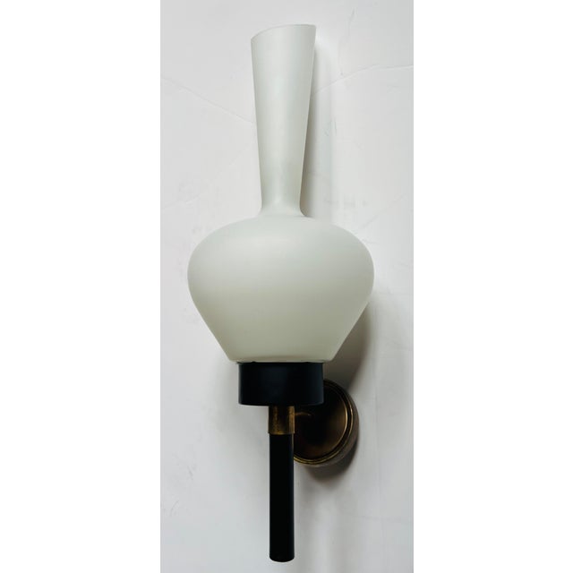 A beautiful large pair of 1950s French wall lights with white elongated glass shades and black enamel and aged brass...