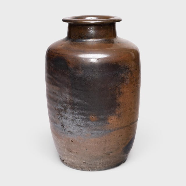 Cloaked inside and out with a warm brown glaze, this antique Chinese pickling pot was originally used for fermenting rice...