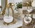 A sculptural gold-tone heron standing gracefully above a carved white marble catchall bowl, creating a decorative object...