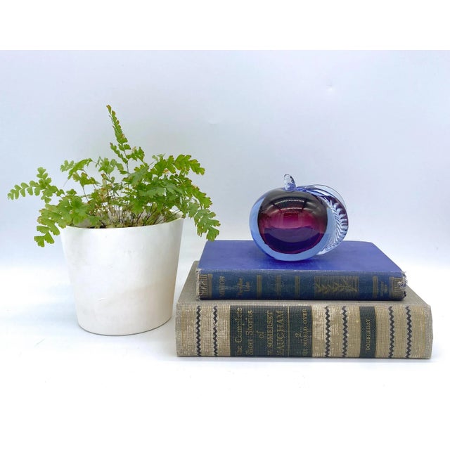Luminescent blown glass paperweight in the shape of an apple. Brilliant red interior is accented blue exterior giving it a...