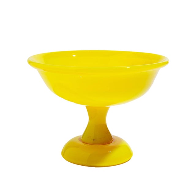 Cadmium yellow opaline art glass compote. The bowl has a folded rim and is supported by a waisted pedestal on a dome...
