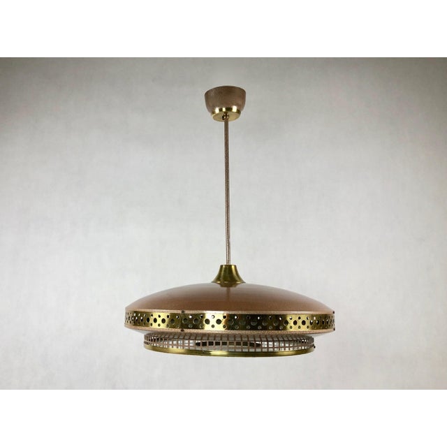 The ceiling lamp was manufactured by L'udib from Bratislava in the 1950s. The upper part and lower rim of the saucer are...