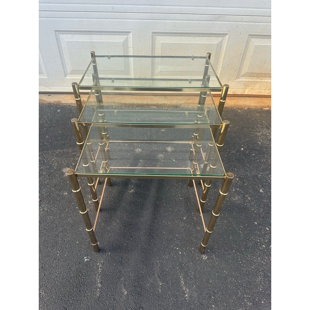 Indulge in the opulence of Hollywood Regency design with this exceptional set of three brass faux bamboo nesting tables in...