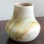 A late-20th century Nemadji Pottery vase with a beautiful swirl pattern of orange and green tones against a bisque-colored...
