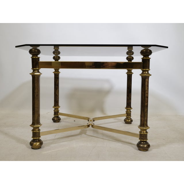 Elegant Hollywood Regency coffee table from the 1970s, crafted from brass and smoked glass. The smoked glass tabletop...