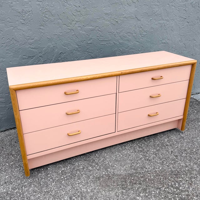 A striking blend of softness and structure, this postmodern dresser features a blush pink high-gloss laminate finish...