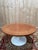 Round dining table in a modern design style, dating from the 1960s. The solid wood top, stained walnut, rests on an...