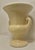 An understated vintage Neoclassical ceramic urn vase executed in a classic campana form. The vessel features a flared rim...