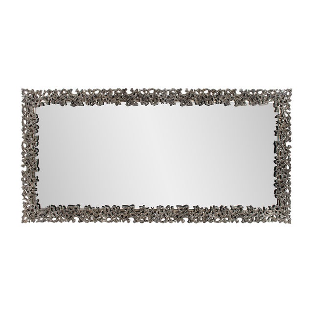 This stunning mirror is framed with an intricate, abstract design that mimics the organic texture of coral or lava rock....