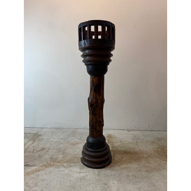 This unique antique wooden plant stand features a rustic, timeworn design with a distinctive wheel axle-inspired base....