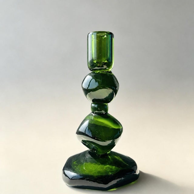 This hand-blown glass candle holder is made of stacked pebbles to form a vertical structure. The large glass body is blown...