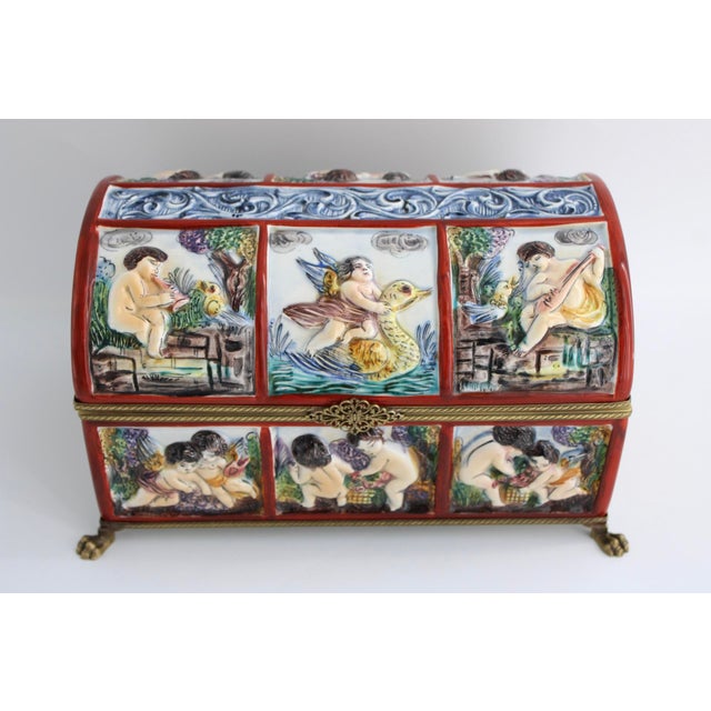 This rare and beautifully shaped domed box is decorated with relief scenes depicting putti/cherubs playing music and other...