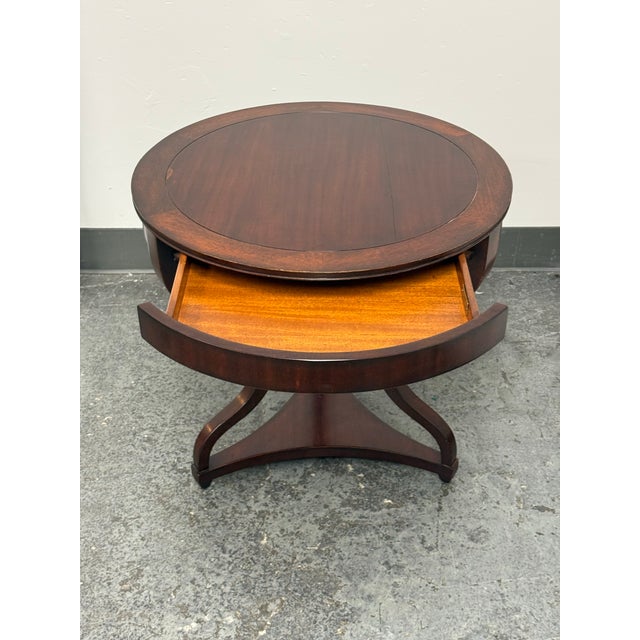 Design Plus Gallery presents an Acquisitions by Henredon Occasional Table. This wood table has a circular top with a...