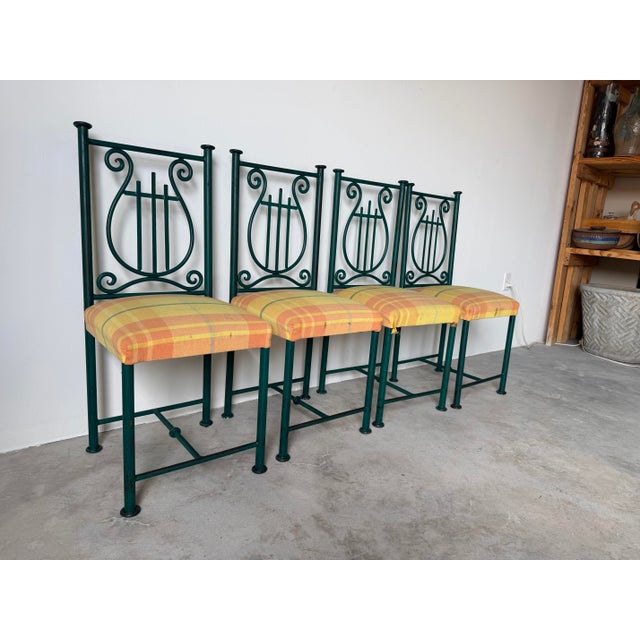 Charming set of four vintage 1980s hand forged metal dining chairs featuring elegant scrollwork and lyre-form backs with a...