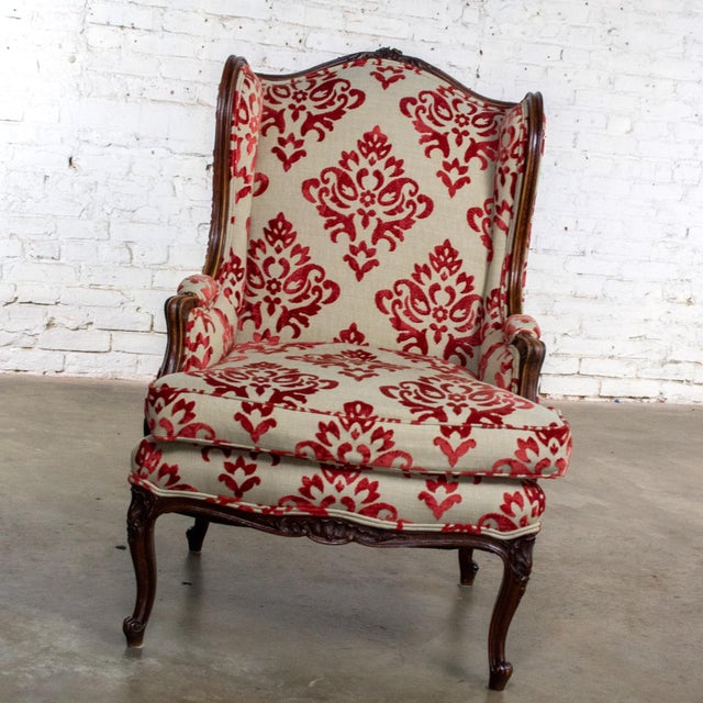Exquisite vintage French Louis XV style wingback armchair composed of a carved walnut frame with cabriole legs, loose...
