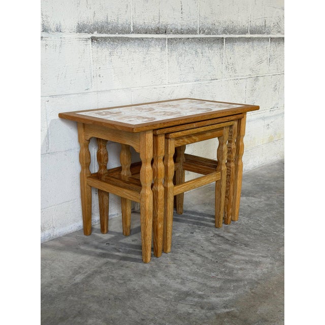 This set of three nesting tables features a convenient space-saving design. Rectangular tops showcase brown scenic tiles...