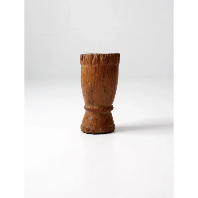 A antique carved wood mortar, sculpted in a tall, slender form with beautifully craggy contours. The naturally weathered...