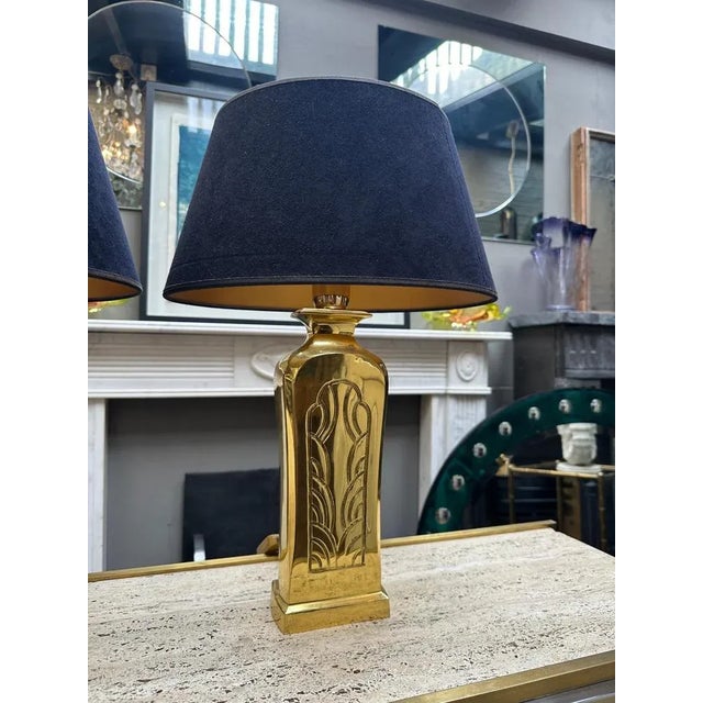A pair of French polished cast brass table lamps with decorative pattern to facia, brushed cotton black shades with gold...