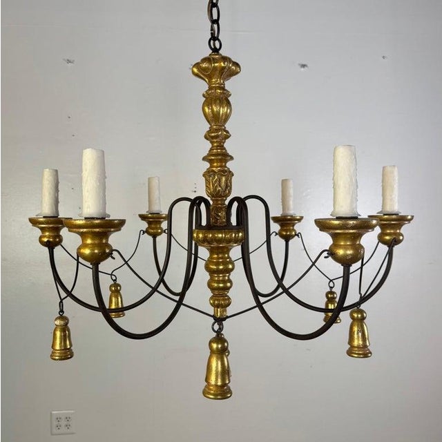 The chandelier features a richly turned and carved central standard in a warm gilt finish, rising to a sculptural...