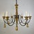 The chandelier features a richly turned and carved central standard in a warm gilt finish, rising to a sculptural...