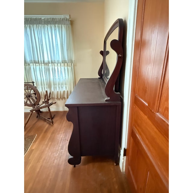 Stunning antique dresser with an attached swivel mirror. This piece features classic Empire-style lines with gracefully...