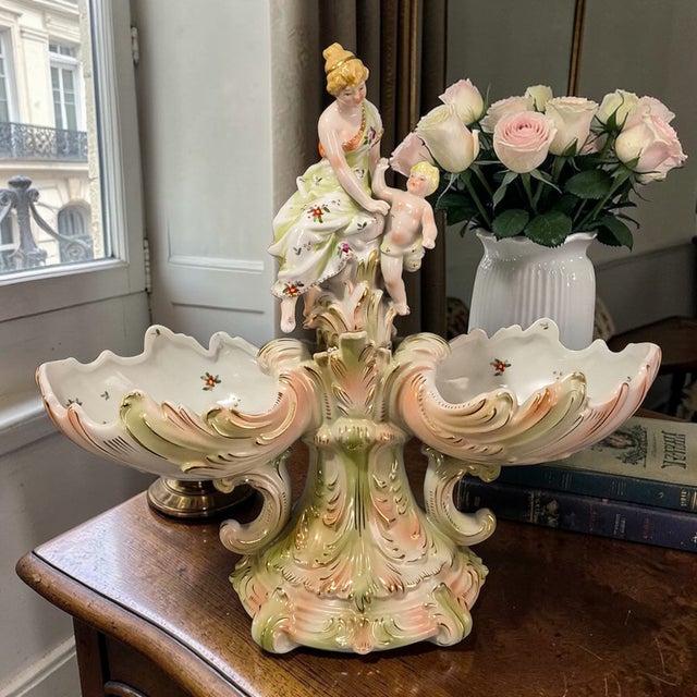 The product is an antique Rococo figurine attributed to Meissen Dresden, featuring a lady with cherub double bowls. Made...