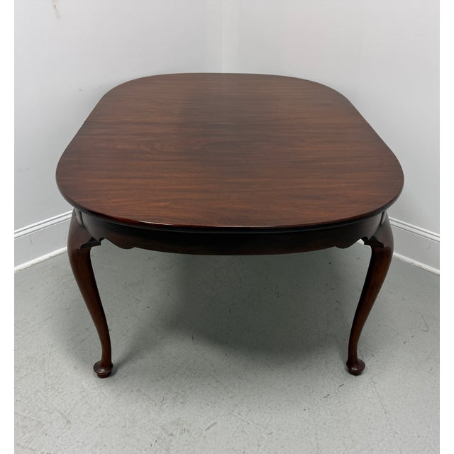 A Queen Anne style oval dining table by Henkel Harris, of Winchester, Virginia, USA. Solid mahogany with rounded edge to...
