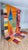 A vivid Boujaad patchwork — one half warm orange, the other deep burgundy and rose — crossed by a chain of four oversized...